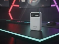 Carregador portátil branco de 10000 mAh com visor digital sobre mesa gamer com iluminação LED.